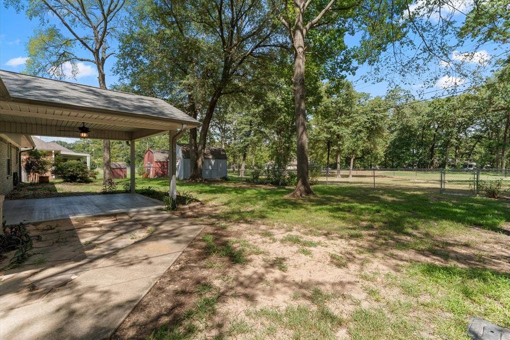 116 Meadowood Road, Enchanted Oaks, TX 75156 Spacious backyard featuring a covered patio, a shed, mature trees, and a chain-link fence