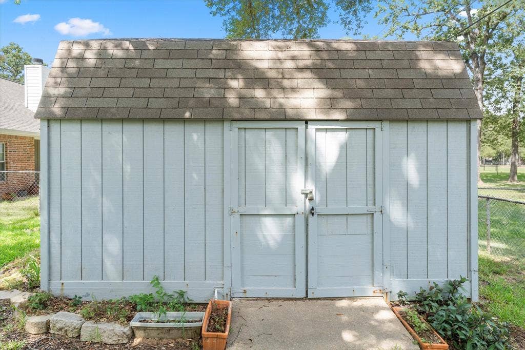 116 Meadowood Road, Enchanted Oaks, TX 75156 Exterior storage shed with vertical panel siding, double barn doors, and an asphalt shingle roof