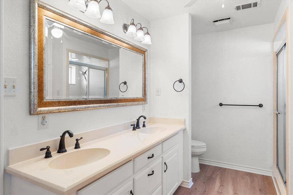116 Meadowood Road, Enchanted Oaks, TX 75156 Bathroom featuring a dual vanity with a light-toned countertop, two integrated sinks, and dark bronze-finish faucets