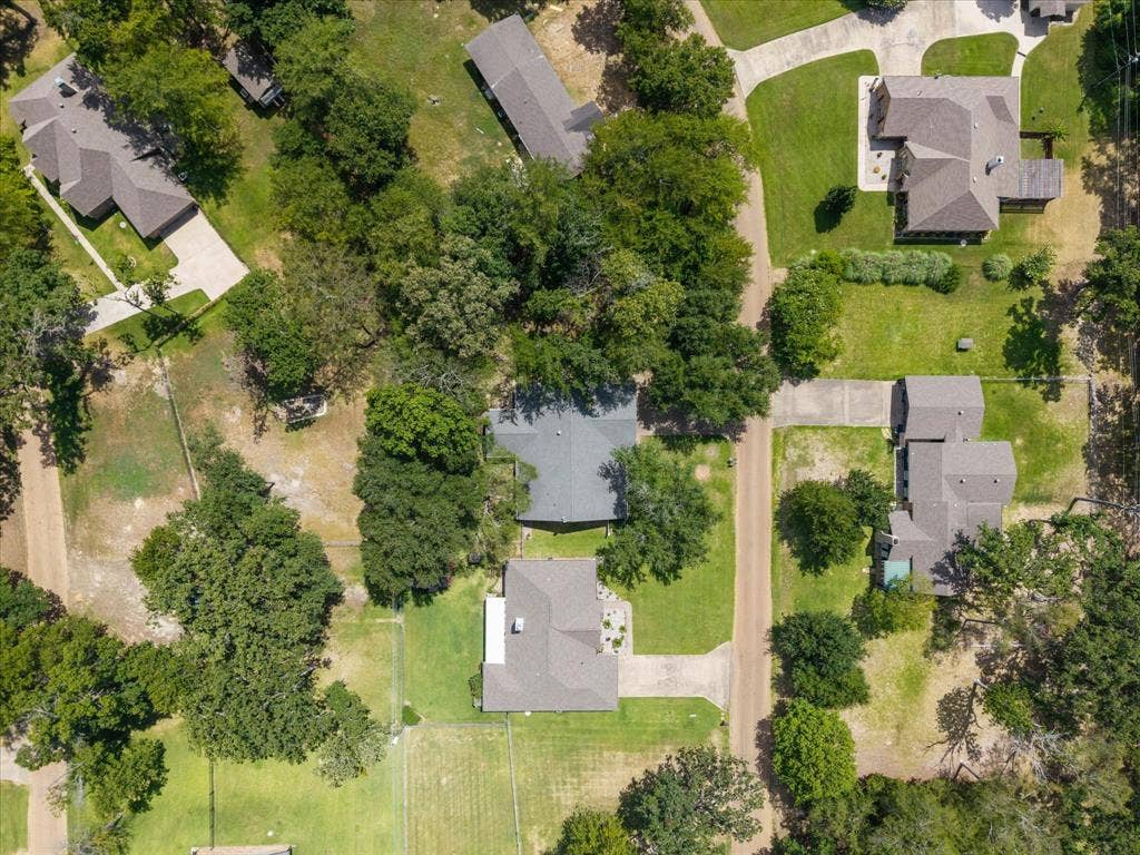 116 Meadowood Road, Enchanted Oaks, TX 75156 Aerial perspective showcasing multiple properties, each featuring a pitched roof, mature trees, and a concrete driveway