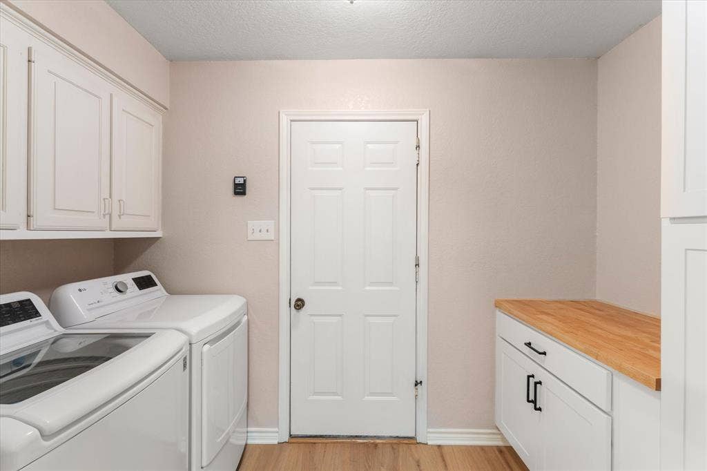 116 Meadowood Road, Enchanted Oaks, TX 75156 Laundry area featuring wood-finish flooring, white cabinetry, a built-in wood countertop, and a solid panel door