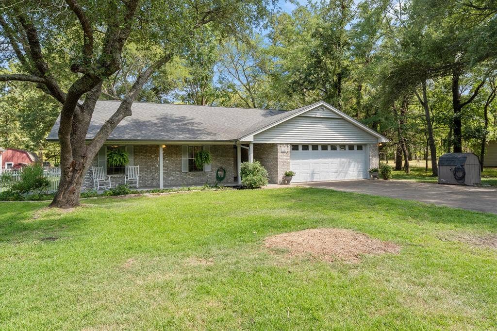 116 Meadowood Road, Enchanted Oaks, TX 75156 Ranch-style residence featuring a brick facade, covered front porch, and an attached two-car garage with a white panel door