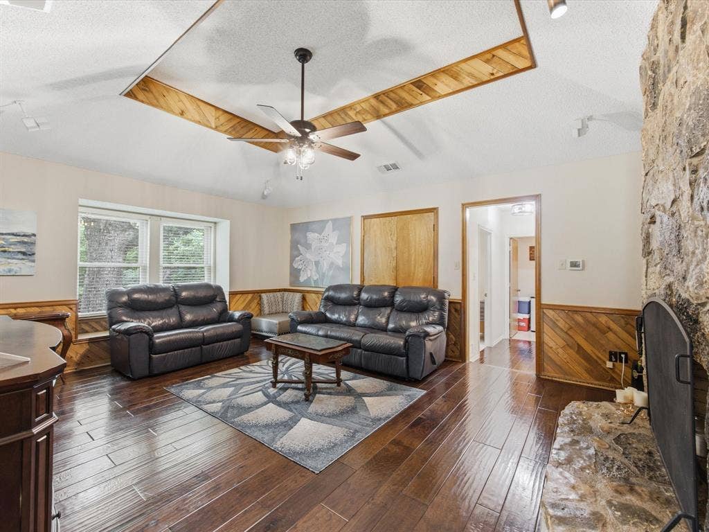 3701 Waycross Court, Arlington, TX 76016 Living area featuring wood-finish flooring, a stone-faced fireplace, and wainscoting