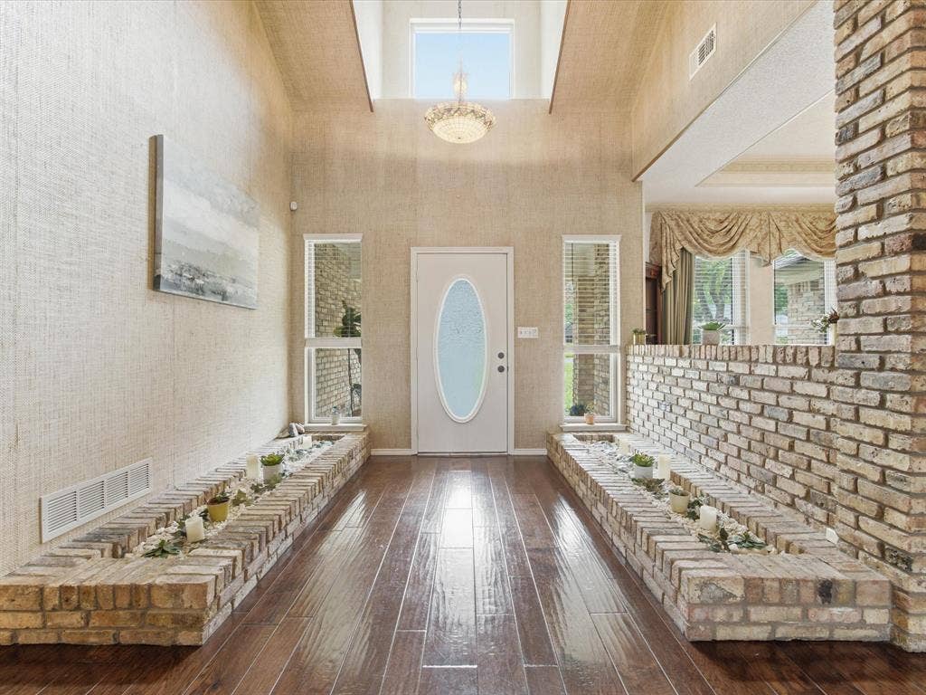 3701 Waycross Court, Arlington, TX 76016 Entryway featuring wood-finish flooring, a white oval-paneled door, and two brick-built planter boxes