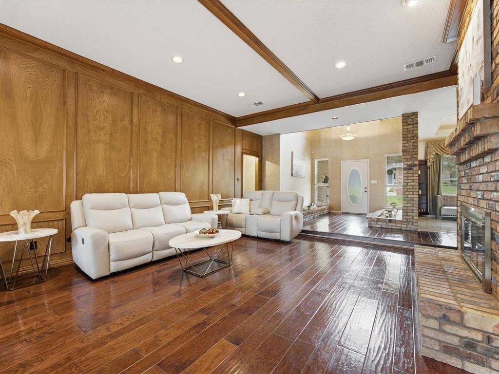 3701 Waycross Court, Arlington, TX 76016 Spacious living area featuring wood-finish flooring, wood paneling, a brick fireplace, exposed wood ceiling beams, and recessed lighting