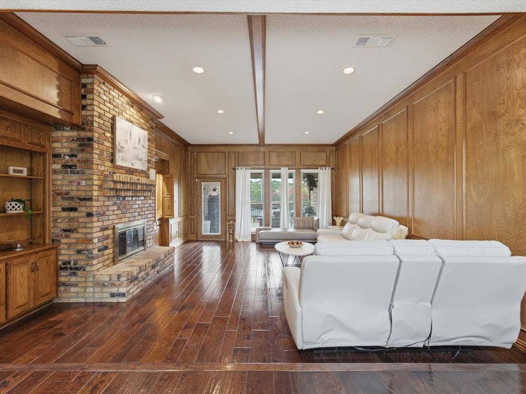 3701 Waycross Court, Arlington, TX 76016 Spacious living area featuring extensive wood paneling, a brick fireplace, built-in shelving, wood-finish flooring, and recessed lighting