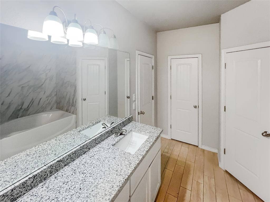Bathroom featuring a dual vanity with a speckled countertop and an undermount sink