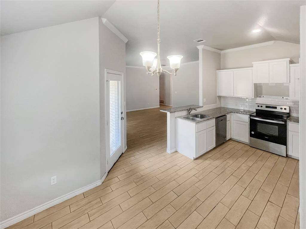 Kitchen featuring white cabinetry, granite-style countertops, stainless steel appliances, and a subway tile backsplash