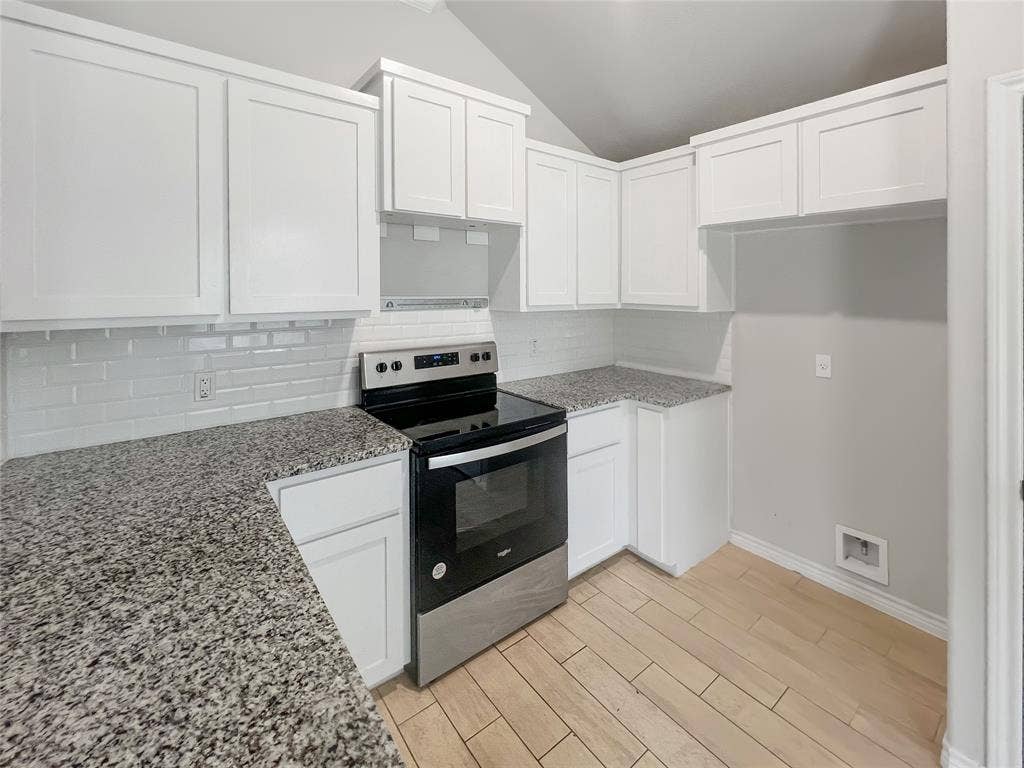 Contemporary kitchen featuring white cabinetry, granite countertops, subway tile backsplash, stainless steel range, and wood-finish flooring