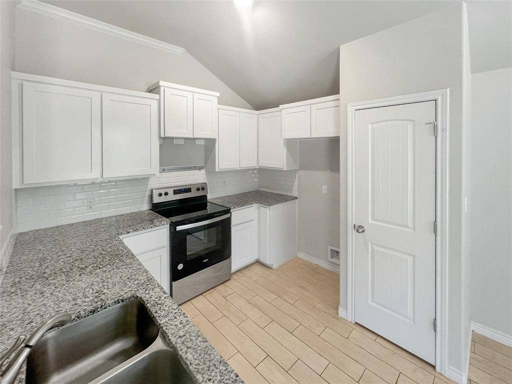 Kitchen featuring white cabinetry, granite countertops, tile backsplash, stainless steel range, and wood-finish flooring