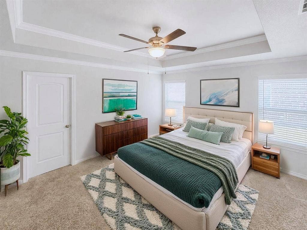Virtually stagedTray ceiling with crown molding and a ceiling fan