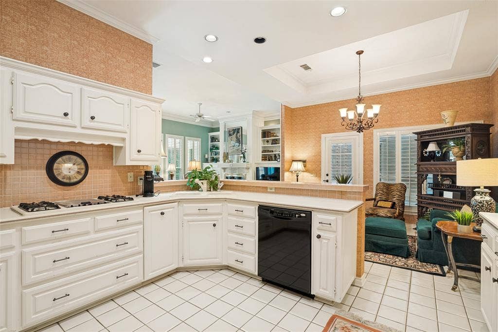White paneled cabinetry in a U-shaped configuration, featuring a gas cooktop, integrated dishwasher, and tile flooring
