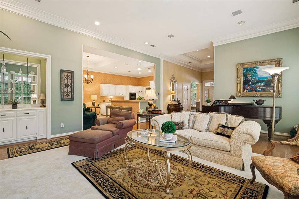 Spacious living area featuring high ceilings with crown molding, recessed lighting, and wood-finish flooring