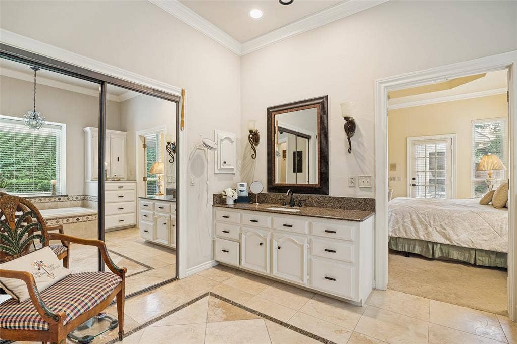 Bathroom vanity featuring a granite countertop, undermount sink, and white cabinetry with dark hardware