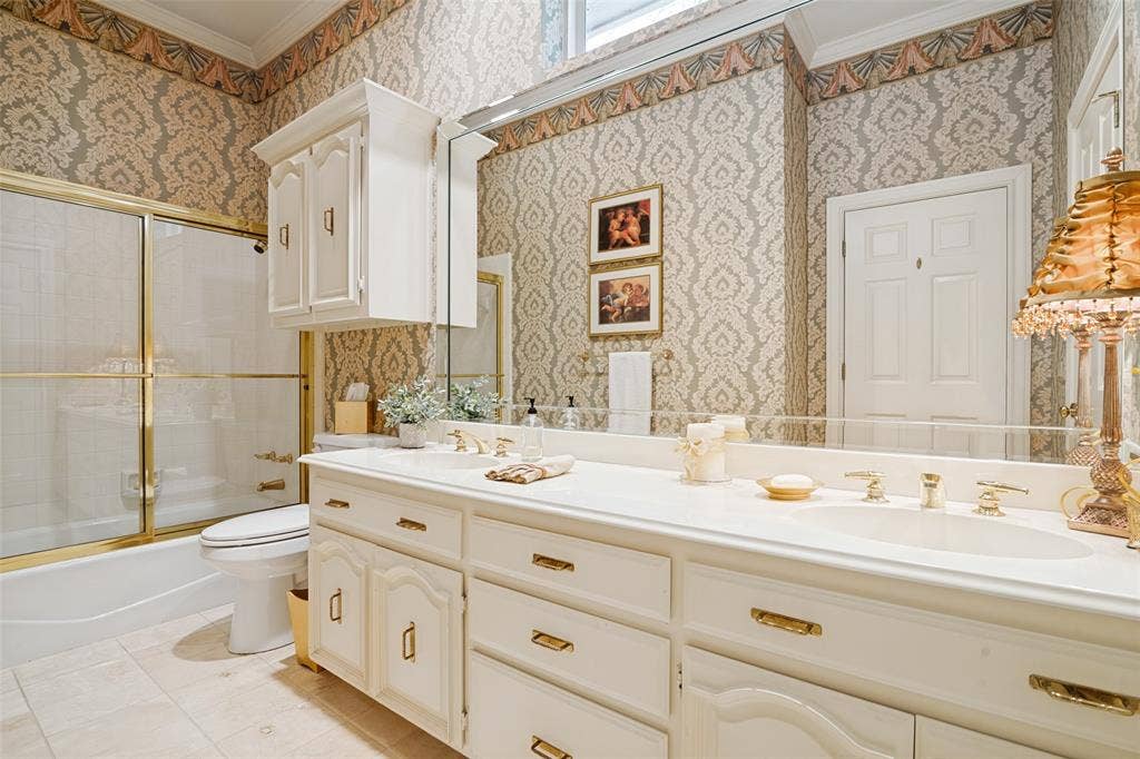 Bathroom featuring a dual vanity with integrated sinks, gold-tone hardware, and a framed mirror
