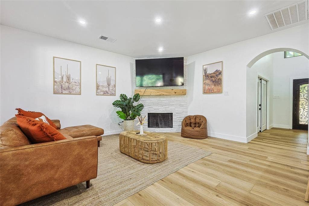 1088 Pondview Drive, Cedar Hill, TX 75104 Living area with arched walkways, a large fireplace, visible vents, and wood finished floors