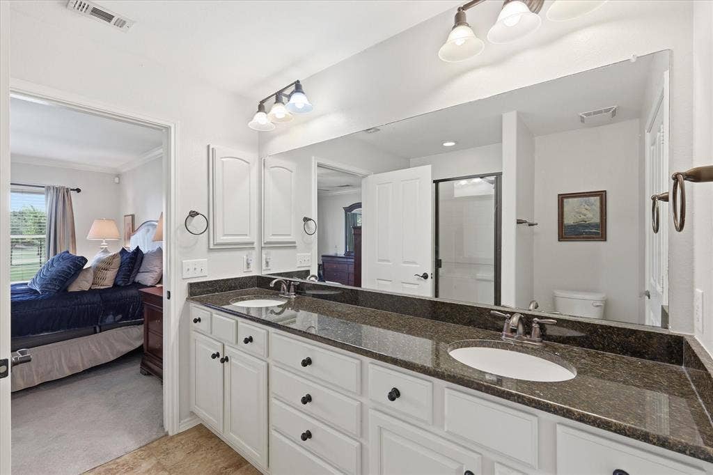 7594 Trull Brook Lane, Frisco, TX 75036 Primary Bathroom with Dual vanity with dark granite countertops and white cabinetry