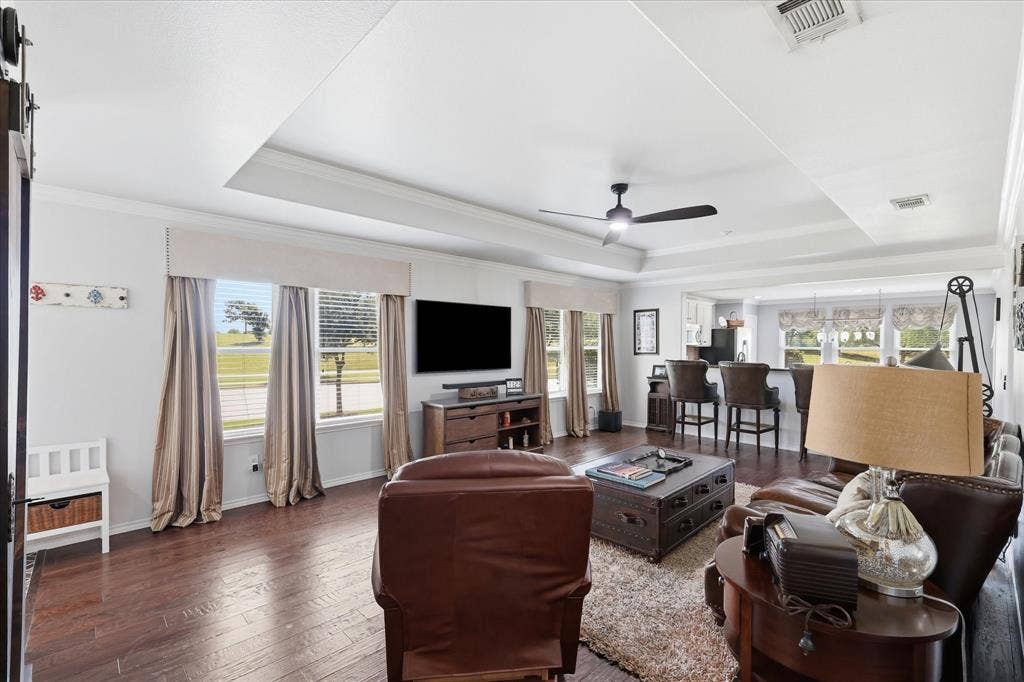 7594 Trull Brook Lane, Frisco, TX 75036 Spacious living area featuring wood-finish flooring, a tray ceiling, and crown molding