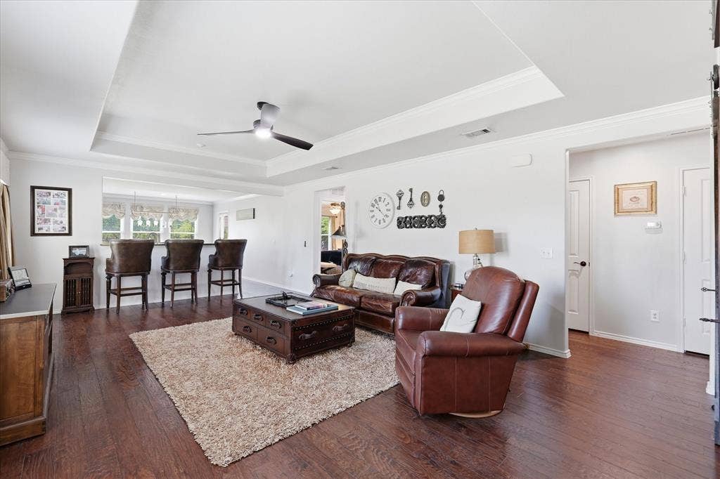 7594 Trull Brook Lane, Frisco, TX 75036 Spacious living area featuring rich wood-finish flooring, a tray ceiling, and a contemporary ceiling fan