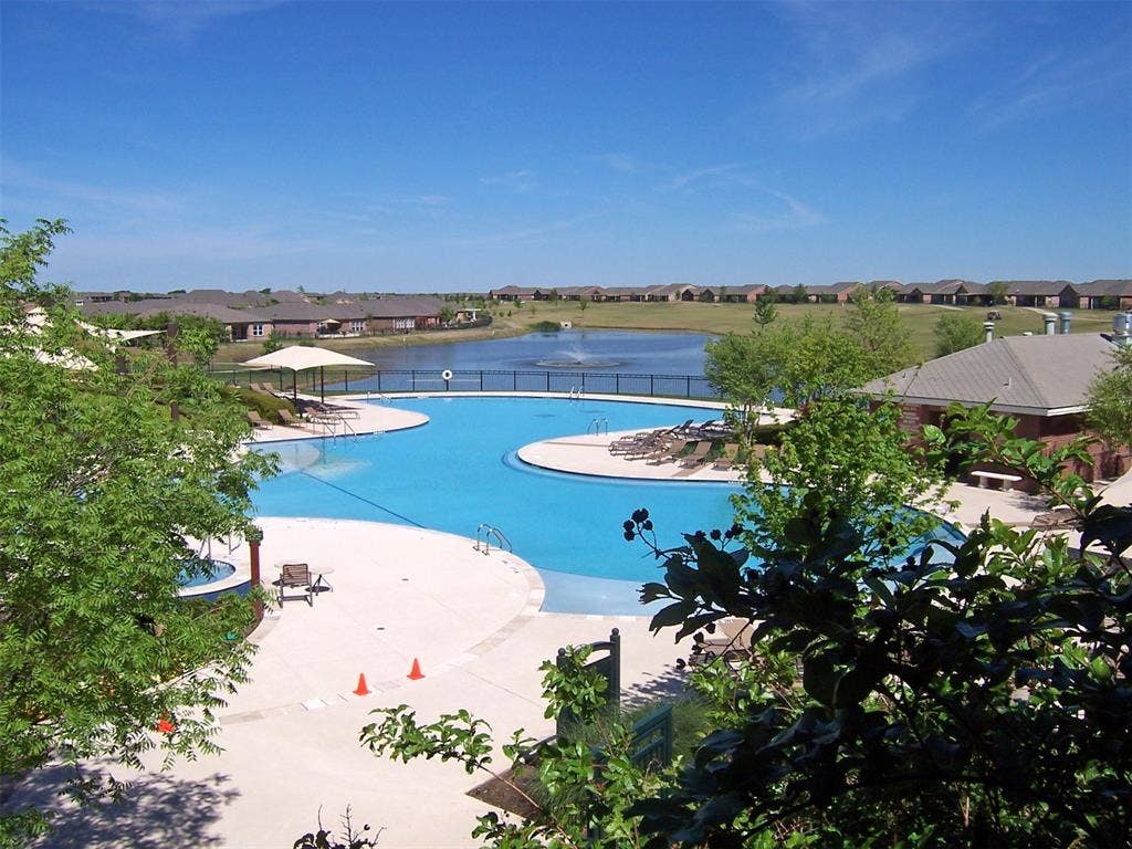 7594 Trull Brook Lane, Frisco, TX 75036 Amenity Center Resort Style Pool with surrounding concrete decking, a shallow wading area, and a separate hot tub