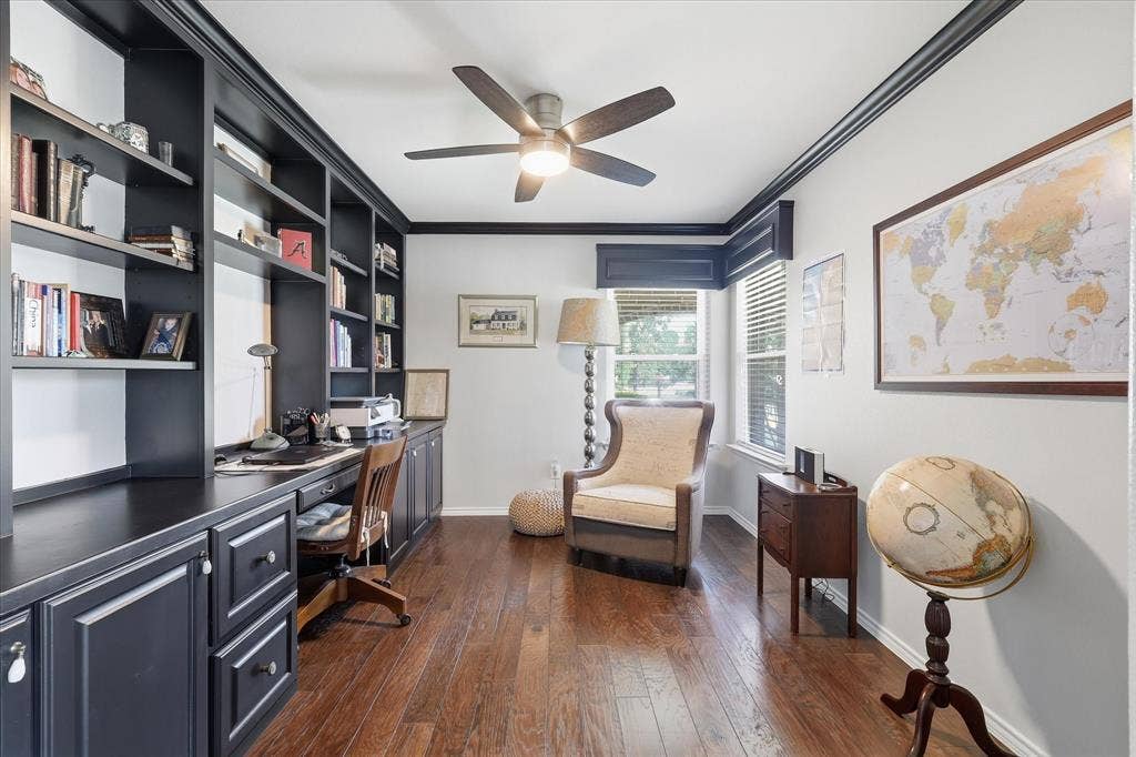 7594 Trull Brook Lane, Frisco, TX 75036 Dedicated office space featuring extensive built-in cabinetry and shelving, dark wood-finish flooring, dark crown molding, and a ceiling fan with integrated lighting