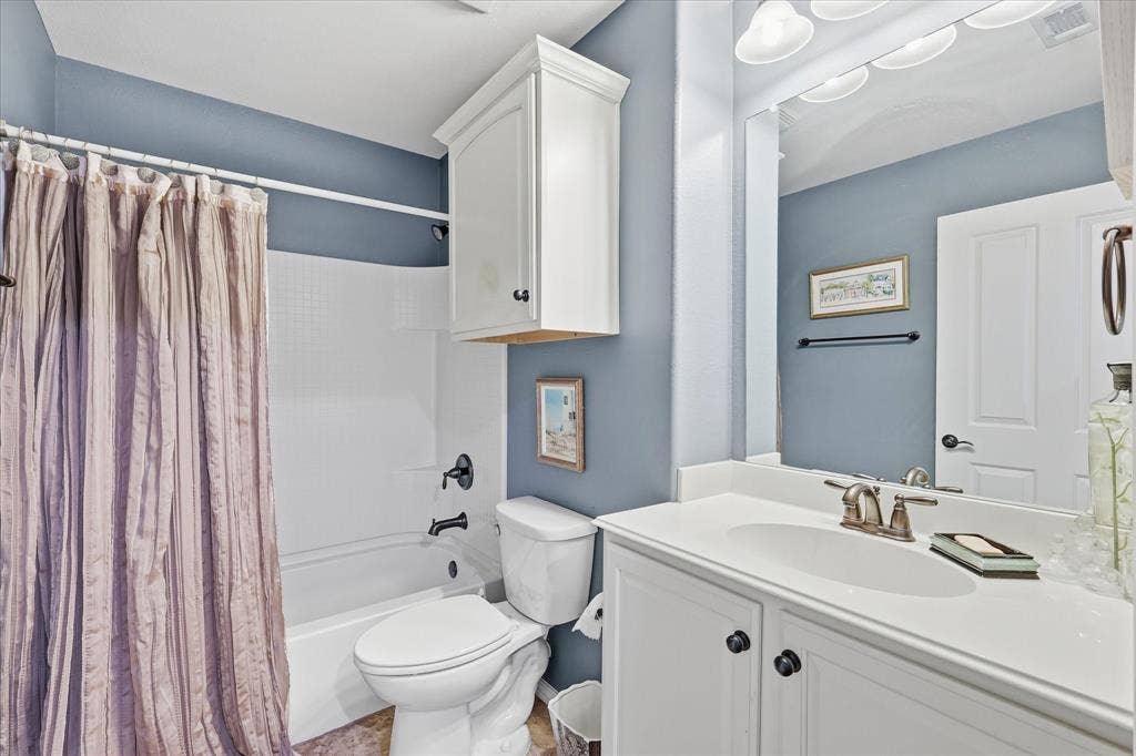 7594 Trull Brook Lane, Frisco, TX 75036 Bathroom featuring a white vanity with integrated sink, brushed nickel faucet, large wall mirror, and white cabinetry