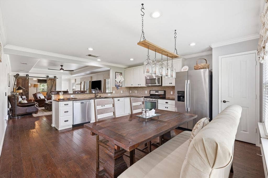 7594 Trull Brook Lane, Frisco, TX 75036 Kitchen featuring wood-finish flooring, white cabinetry, stainless steel appliances, and a tile backsplash