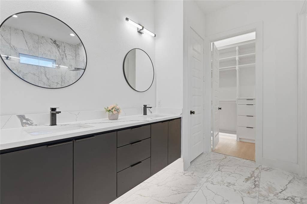Bathroom featuring a dual vanity with dark flat-panel cabinetry, white countertops, and integrated rectangular sinks