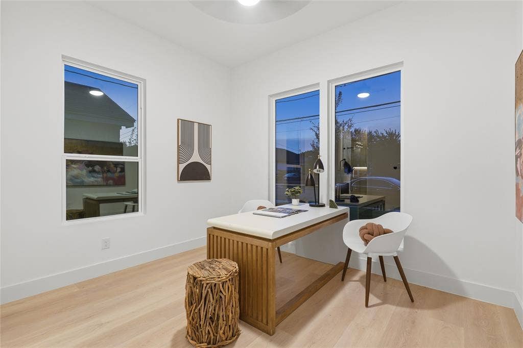Bright room featuring two large windows, light wood-finish flooring, white walls, and a contemporary ceiling light fixture