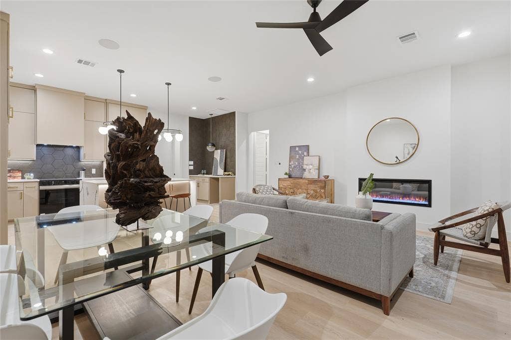 Open-concept living space featuring wood-finish flooring, a linear electric fireplace, and a contemporary ceiling fan