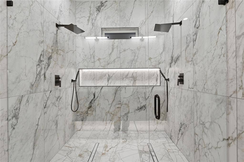 Spacious walk-in shower featuring marble-look wall and floor tiling