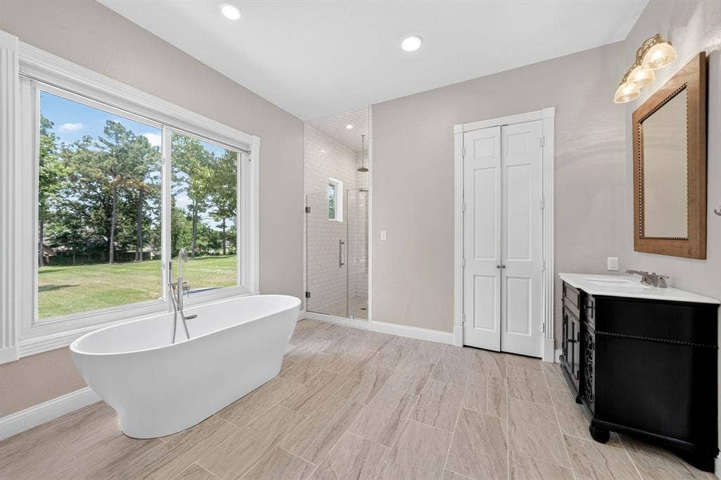 1201 Robbins Road, Athens, TX 75751 1st Floor- Primary Bathroom featuring a standalone soaking tub, glass shower, separate walk-in closets & separate vanities.