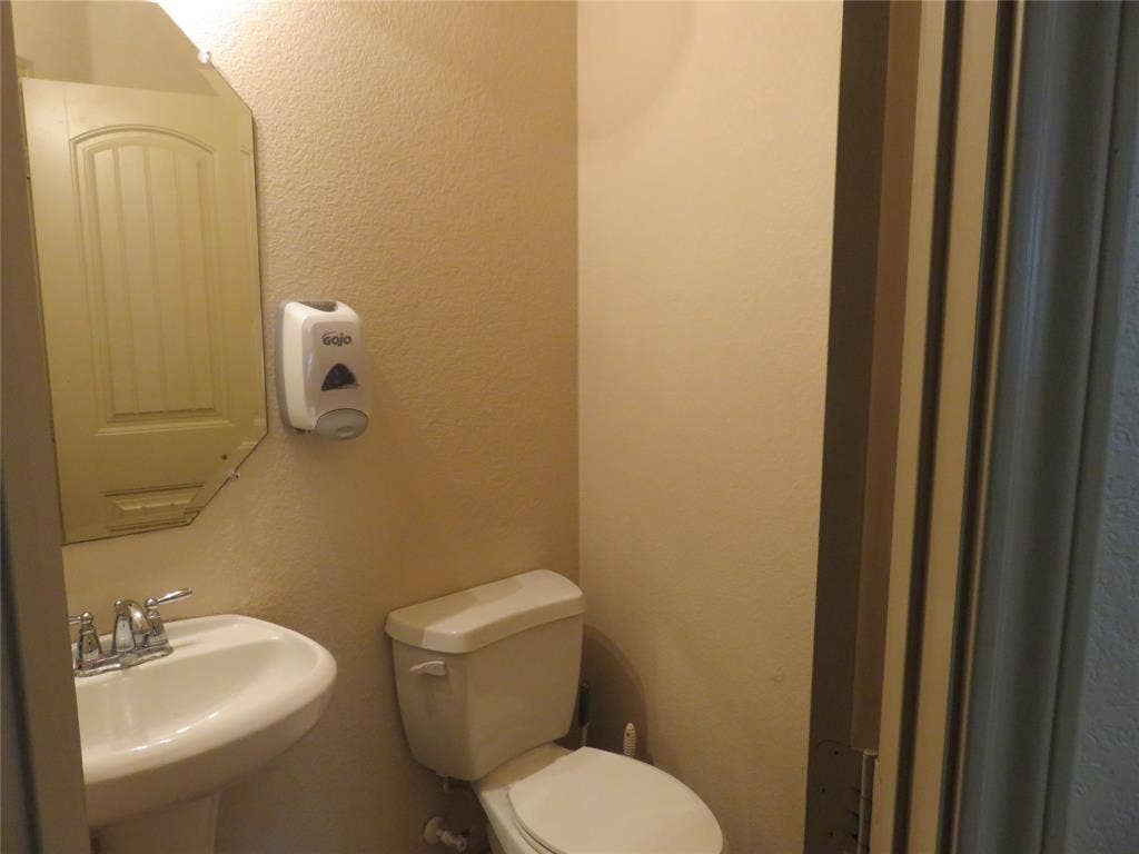 1122 Walter Stephenson Road, Midlothian, TX 76065 Pedestal sink with chrome fixtures, an octagonal mirror, and a white toilet
