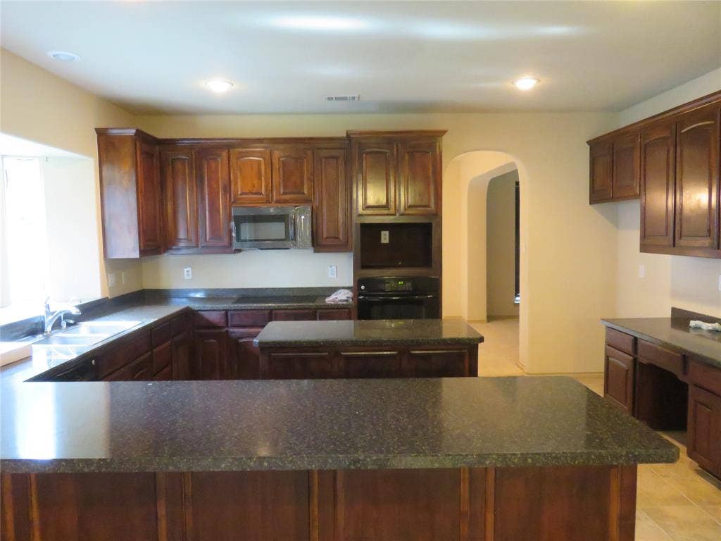 1122 Walter Stephenson Road, Midlothian, TX 76065 Spacious kitchen featuring rich wood cabinetry, dark speckled countertops, a built-in microwave, and recessed ceiling lighting