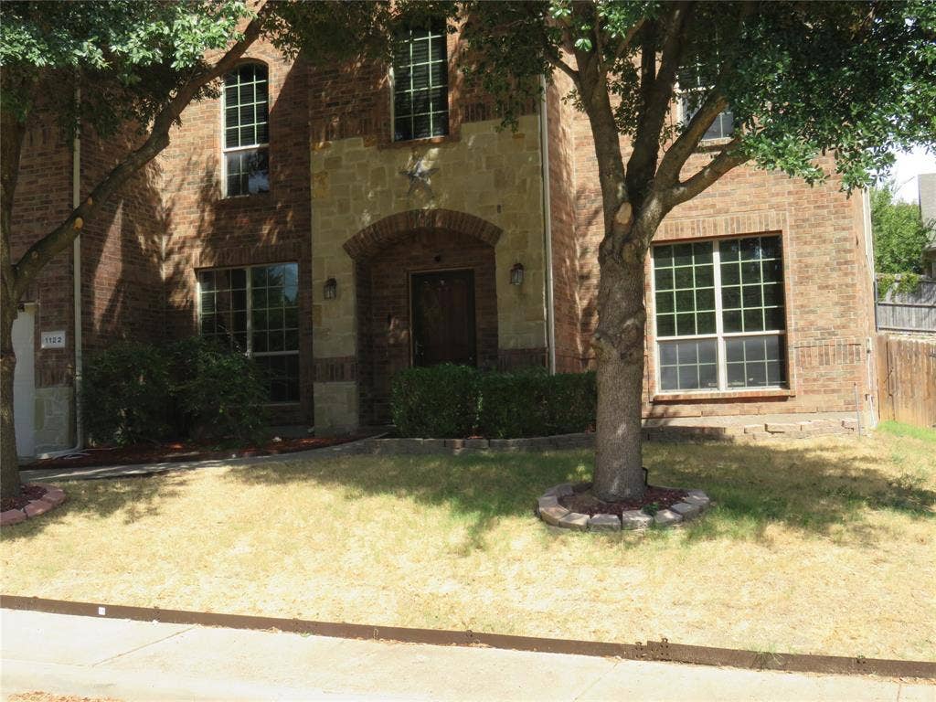1122 Walter Stephenson Road, Midlothian, TX 76065 Brick facade with stone accents, arched entryway, and multiple grid-pattern windows