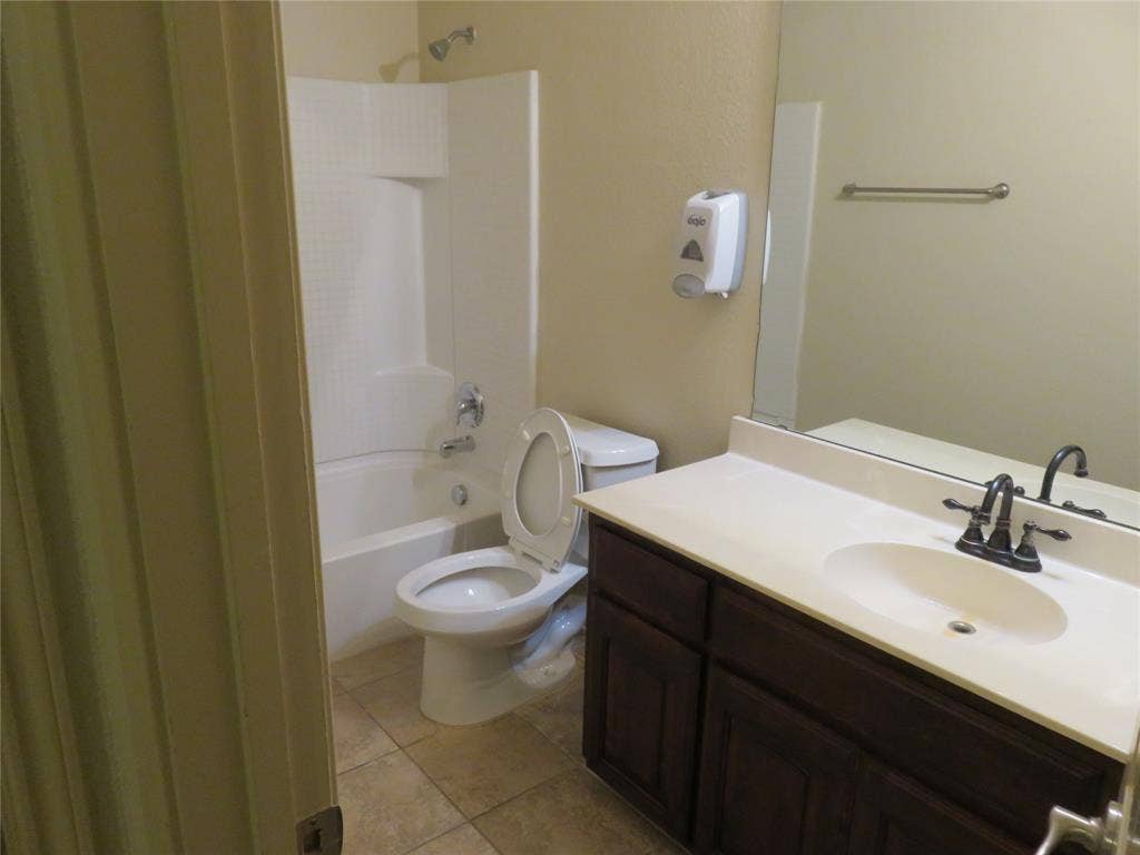 1122 Walter Stephenson Road, Midlothian, TX 76065 Bathroom featuring a dark wood-finish vanity with an integrated sink, a large wall mirror, and a white bathtub with an overhead shower