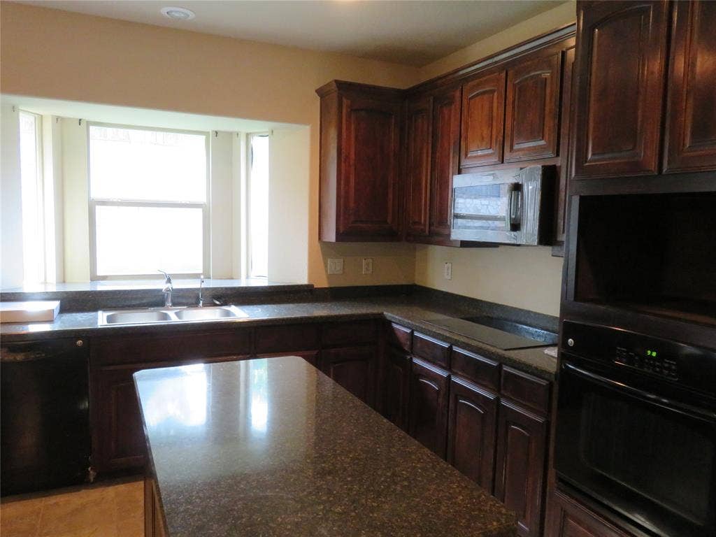1122 Walter Stephenson Road, Midlothian, TX 76065 Kitchen featuring dark wood cabinetry, a built-in oven, integrated microwave, and a black cooktop