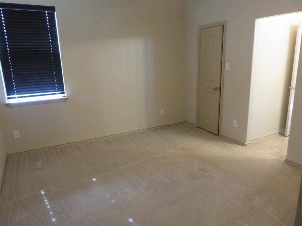 1122 Walter Stephenson Road, Midlothian, TX 76065 Carpeted room featuring a window with horizontal blinds, a panel door with a silver handle, and light-colored walls
