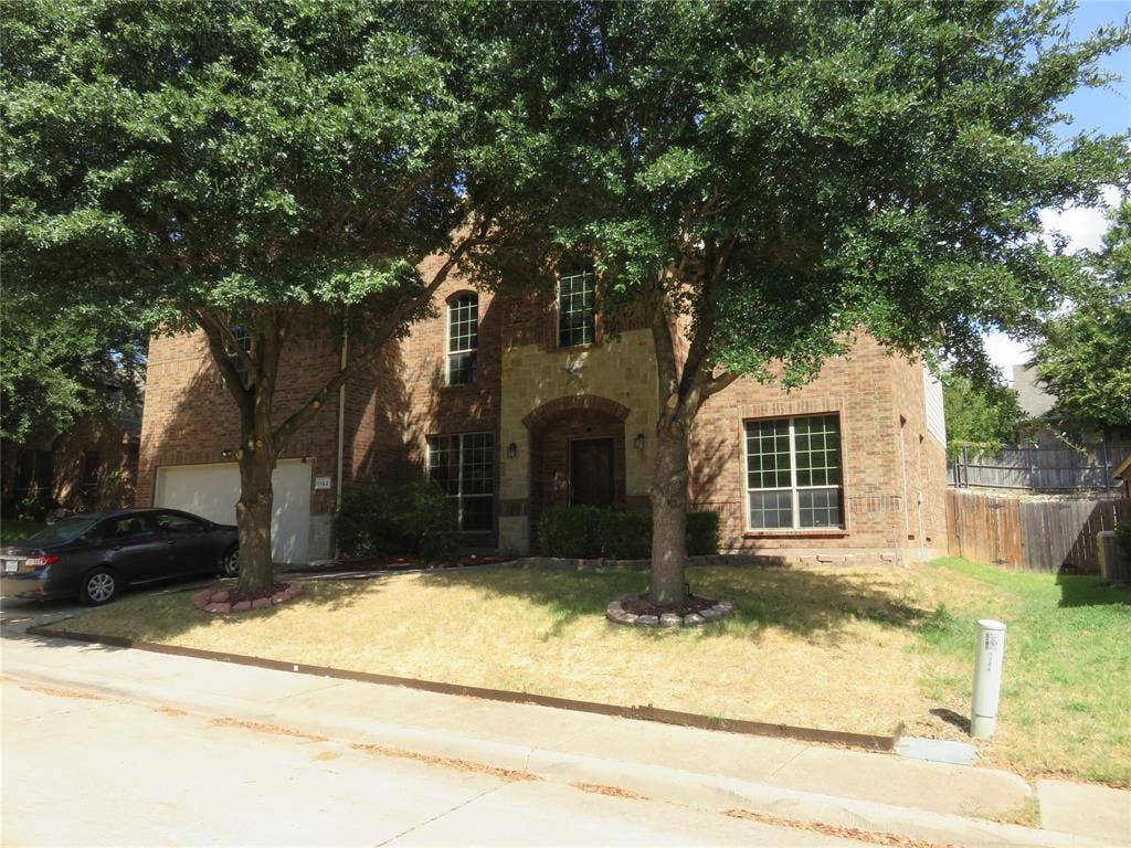 1122 Walter Stephenson Road, Midlothian, TX 76065 Brick exterior with stone accents, arched entryway, attached garage, and mature trees