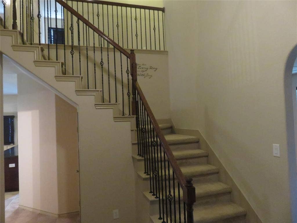1122 Walter Stephenson Road, Midlothian, TX 76065 Dual-level staircase featuring carpeted treads and risers, wrought iron balusters with decorative elements, and a wood-finish handrail