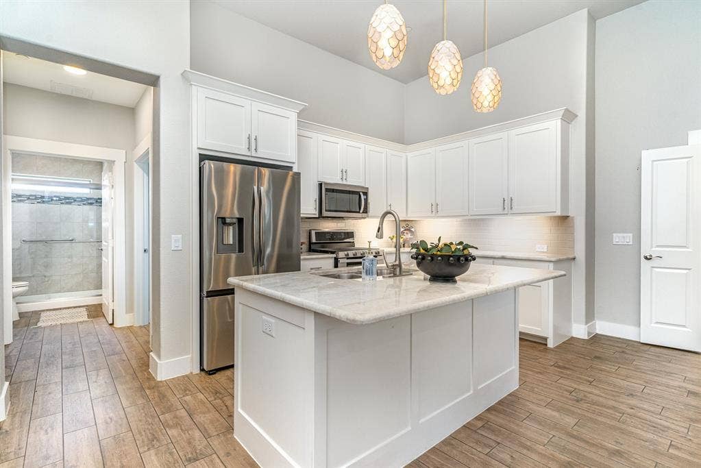 3861 Dalea Drive, Prosper, TX 75078 Modern kitchen featuring an island with a light-toned countertop, white cabinetry with stainless steel hardware, and integrated stainless steel appliances