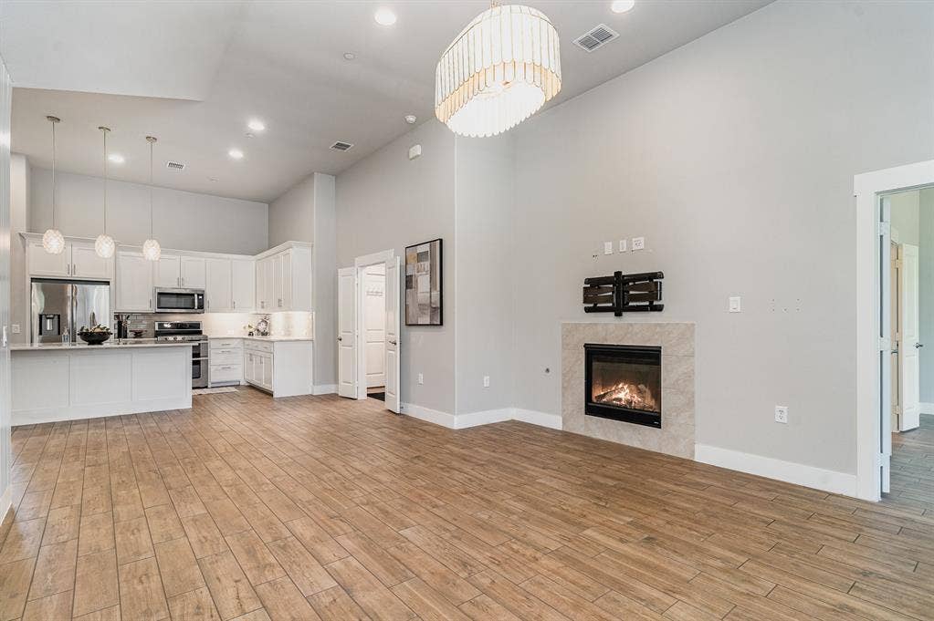 3861 Dalea Drive, Prosper, TX 75078 Open-concept living space featuring wood-finish flooring, a contemporary fireplace with a tiled surround, a modern chandelier, and recessed lighting