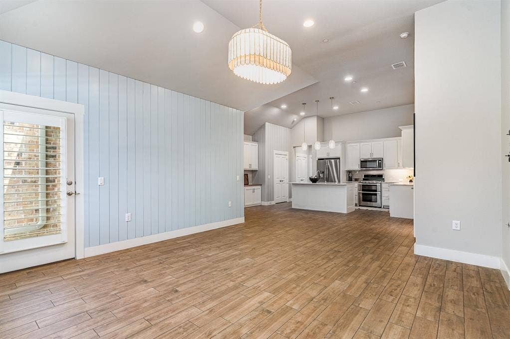 3861 Dalea Drive, Prosper, TX 75078 Spacious living area featuring wood-finish flooring, a decorative chandelier, and vaulted ceilings