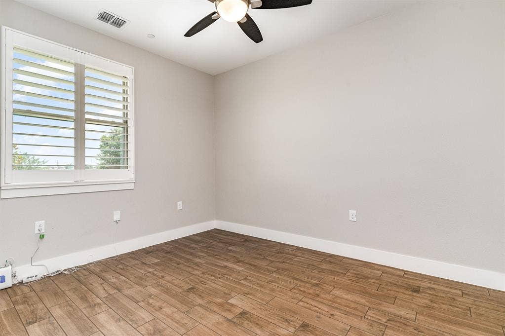 3861 Dalea Drive, Prosper, TX 75078 Secondary Bedroom featuring wood-finish flooring, a window with plantation shutters, a ceiling fan, and light gray walls