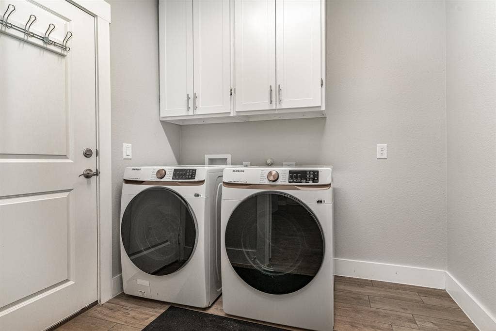 3861 Dalea Drive, Prosper, TX 75078 Laundry area featuring wood-finish flooring, light gray walls, white baseboards, and upper white cabinetry with silver hardware