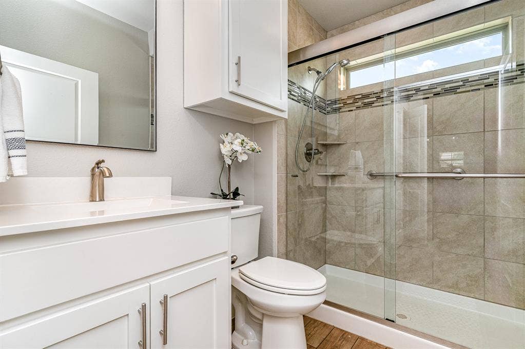 3861 Dalea Drive, Prosper, TX 75078 Secondary Bathroom featuring a white vanity with brushed nickel hardware, a rectangular mirror, and an enclosed shower with a clear glass door