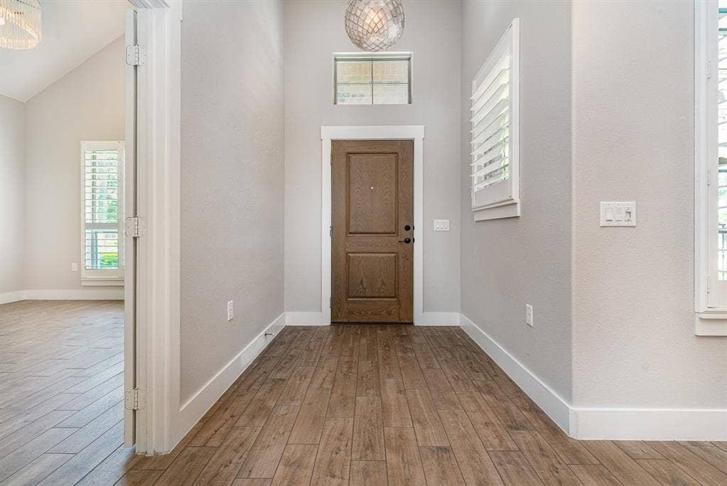 3861 Dalea Drive, Prosper, TX 75078 Entryway featuring wood-finish flooring, a wood-finish entry door, a transom window, and a decorative pendant light fixture