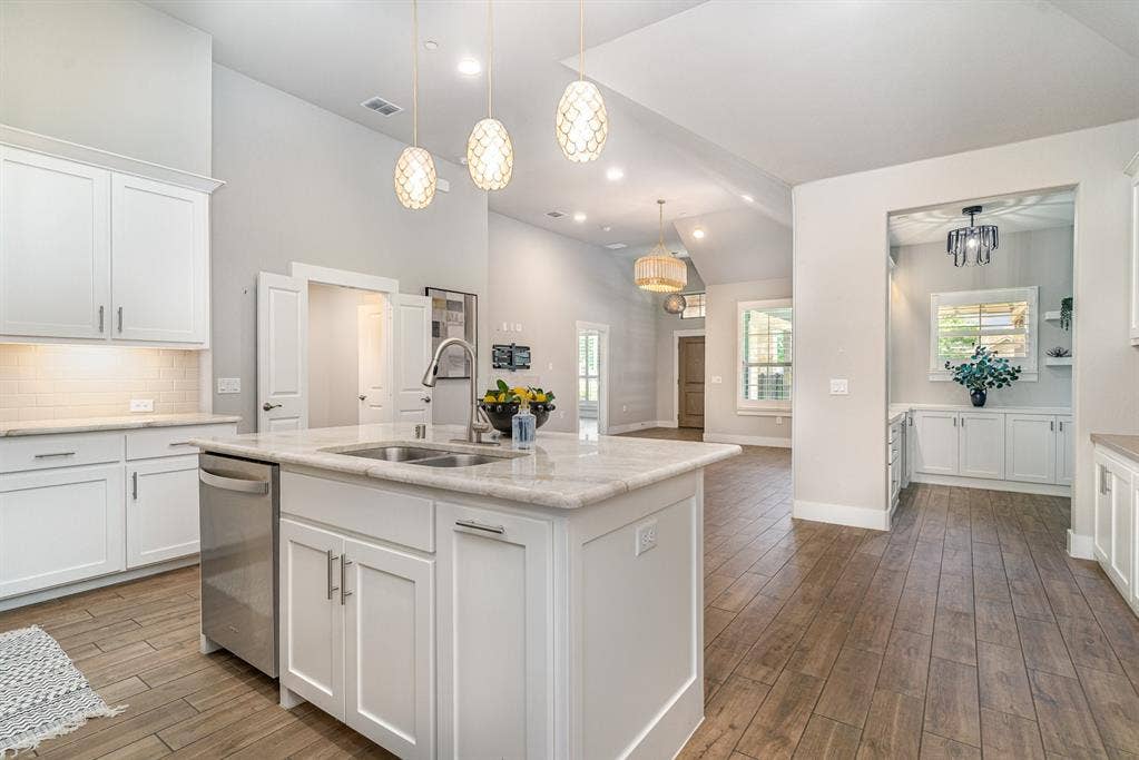 3861 Dalea Drive, Prosper, TX 75078 Kitchen island with a double basin sink, white cabinetry, integrated stainless steel dishwasher, and stone countertop