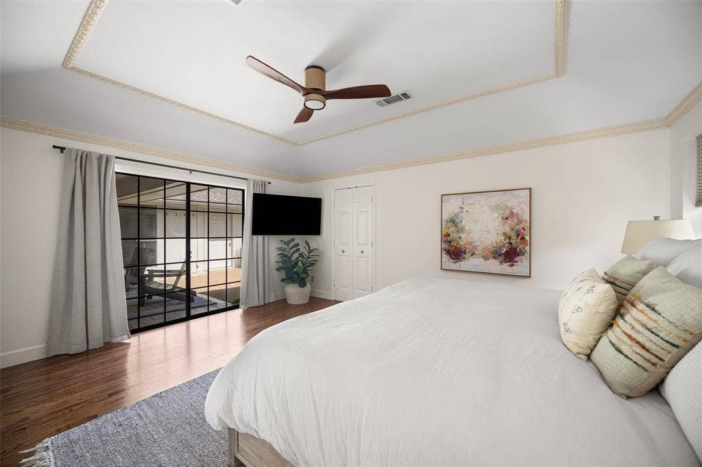 6501 Copper Creek Drive, Dallas, TX 75248 Tray ceiling with decorative molding, wood-finish flooring, and black-framed glass sliding doors leading to an outdoor space