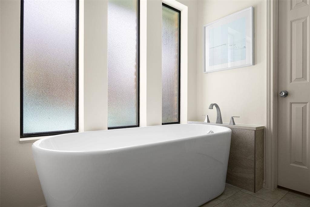 6501 Copper Creek Drive, Dallas, TX 75248 Freestanding soaking tub with brushed nickel fixtures, complemented by a stone-finish tub surround